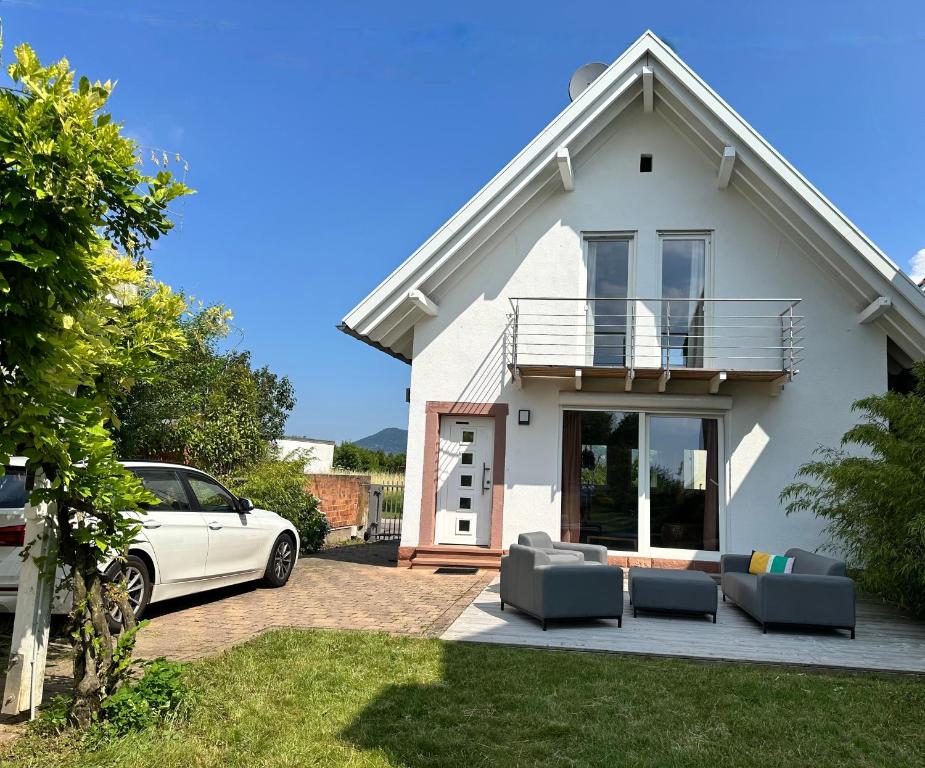 a white house with a car parked in front of it at Ferienhaus Wein & Wald mit Gartensauna in Landau in der Pfalz