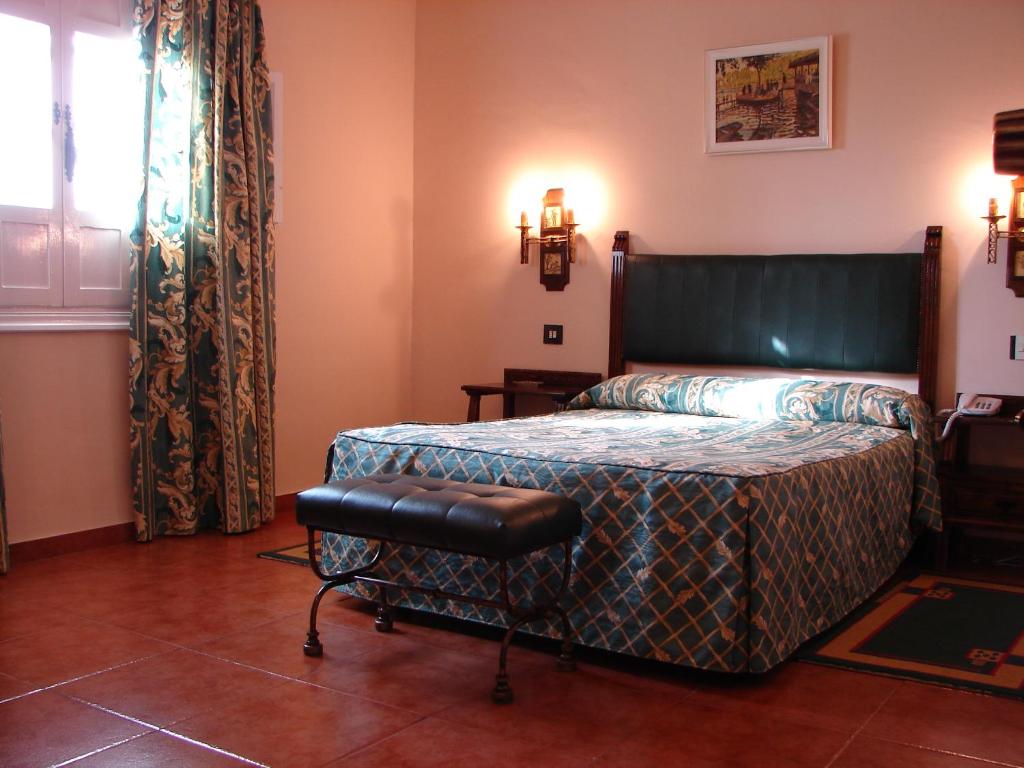 a bedroom with a bed and a bench in it at Hotel Temple Pradorrey in Astorga