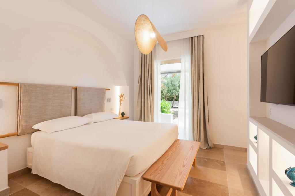 a white bedroom with a bed and a television at Ostuni a Mare in Ostuni