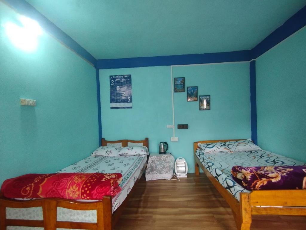 チェラプンジにあるBetzer homestayの青い壁の部屋にベッドが2つある
