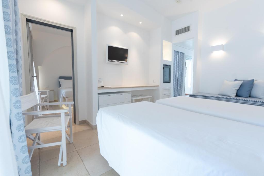 a white bedroom with a white bed and a mirror at Ostuni a Mare in Ostuni