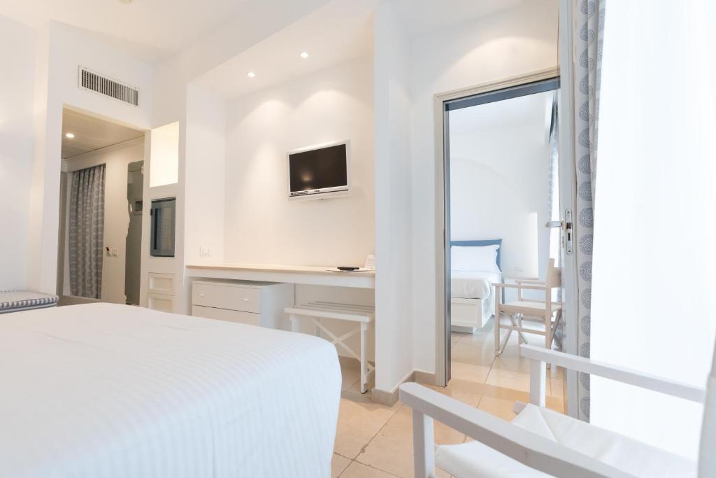 a bedroom with a bed and a desk with a television at Ostuni a Mare in Ostuni