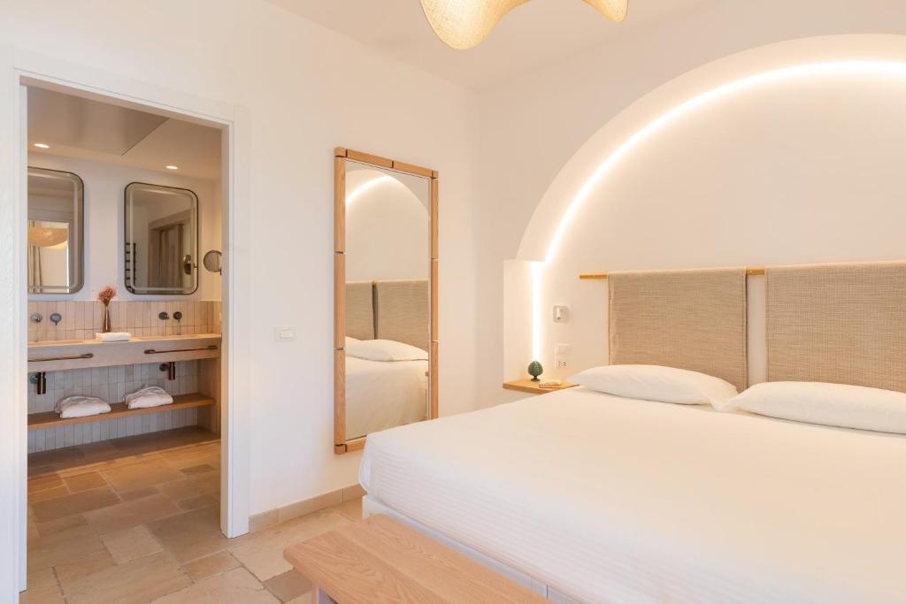 a white bedroom with a large bed and a bathroom at Ostuni a Mare in Ostuni