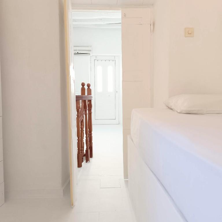 a white bedroom with a bed and a hallway at Perno in Serifos Chora