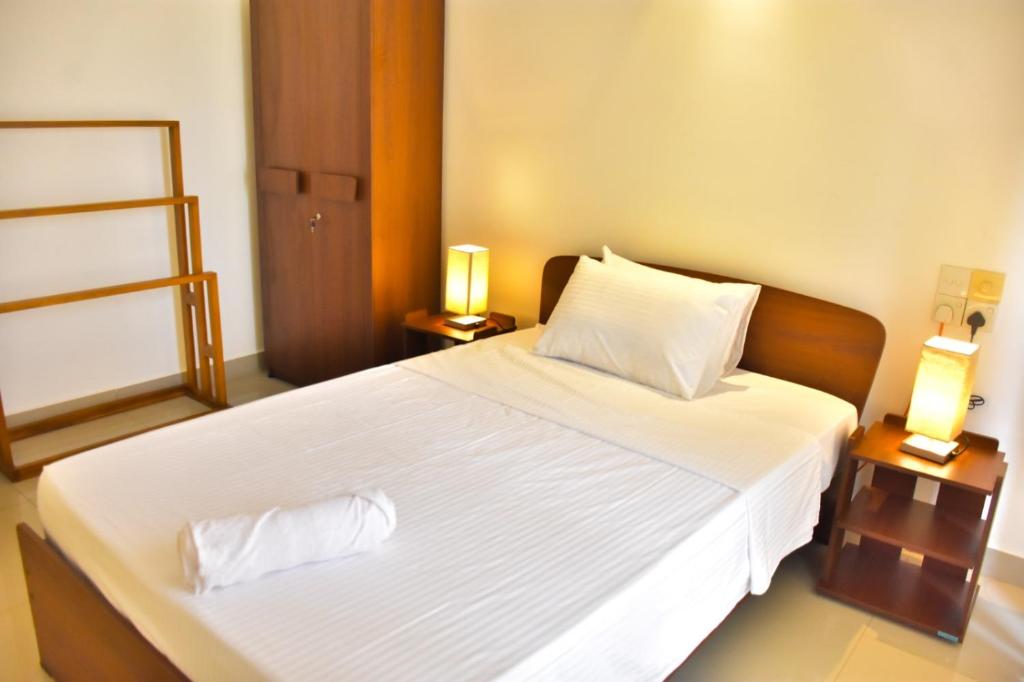 a bedroom with a large white bed with two lamps at Lotus Luxe Residences in Kirillapone