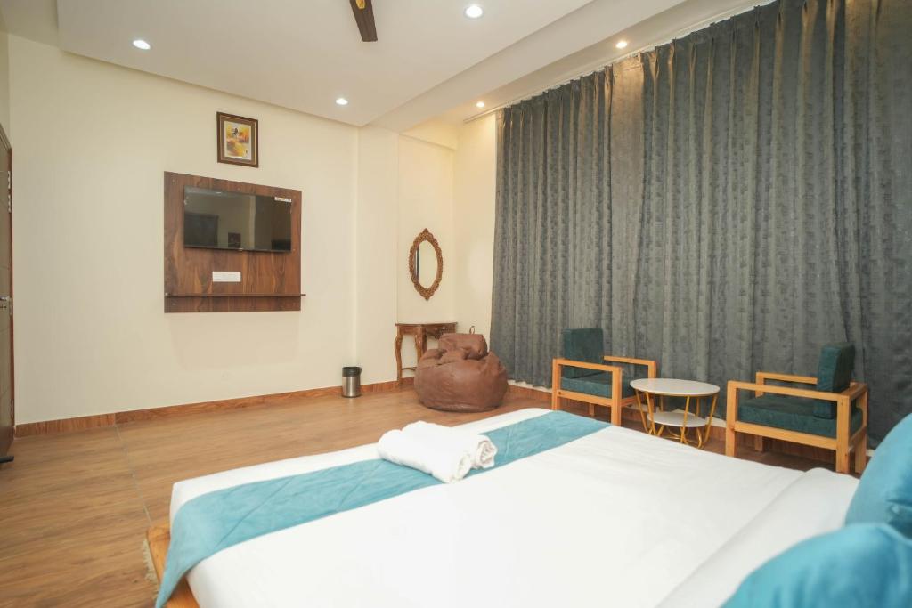 a bedroom with a bed and a television and chairs at Kasauli Vista in Kasauli