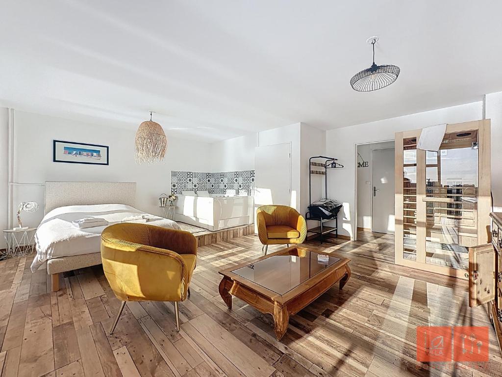 a bedroom with a bed and two chairs and a table at La détente en amoureux in Boulogne-sur-Mer