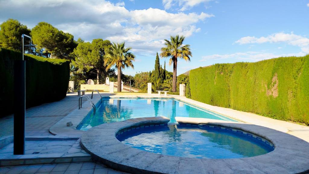 ein Swimmingpool in einem Garten mit Palmen in der Unterkunft Naranjos House in Muntanya la Sella