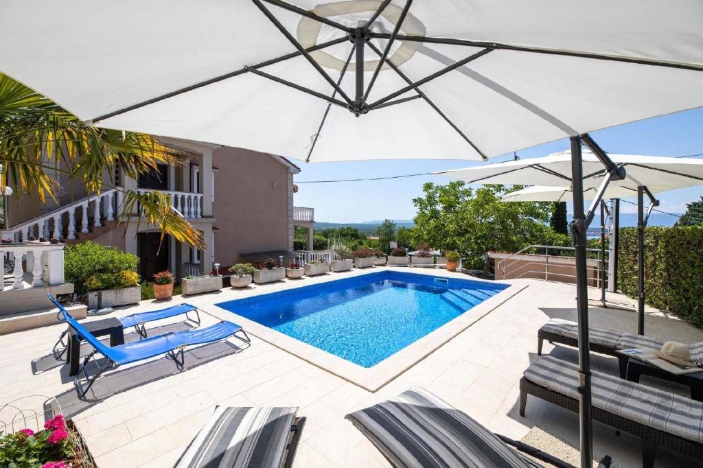 una piscina con ombrellone su un patio di Ferienwohnung für 6 Personen ca 74 qm in Sveti Vid-Miholjice, Kvarner Bucht Krk a Sveti Vid-Miholjice