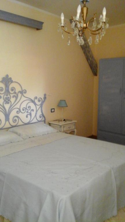 a bedroom with a white bed and a chandelier at Lavanda e Rosmarino in Sandigliano