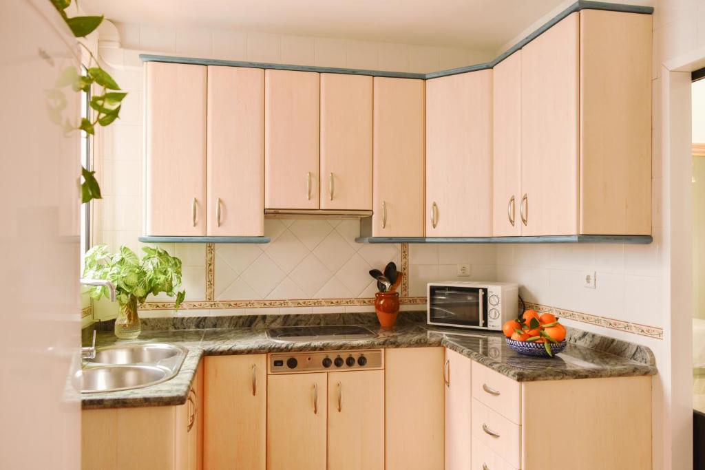 a kitchen with white cabinets and a sink and a microwave at Casa abuela Ana in Padul