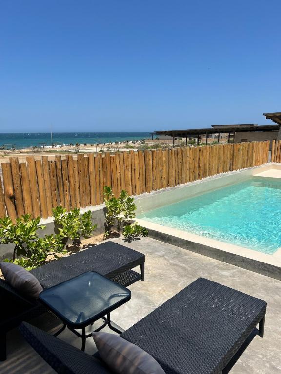 a swimming pool next to a wooden fence at La Morada Punta Sal - Casa de playa frente al mar in Canoas de Punta Sal