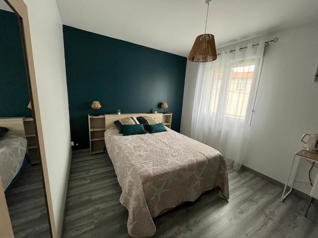 une chambre avec un lit et un mur bleu dans l'établissement 1 Chambre chez lulu, à Riom