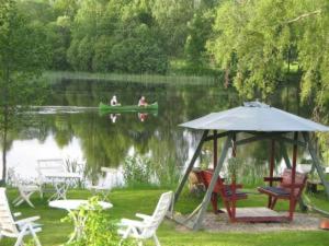 a gazebo next to a lake with people in a boat at Lottas Rum in Smedjebacken