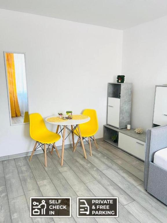 jadalnia ze stołem i żółtymi krzesłami w obiekcie Miha modern and central apartament w mieście Arad
