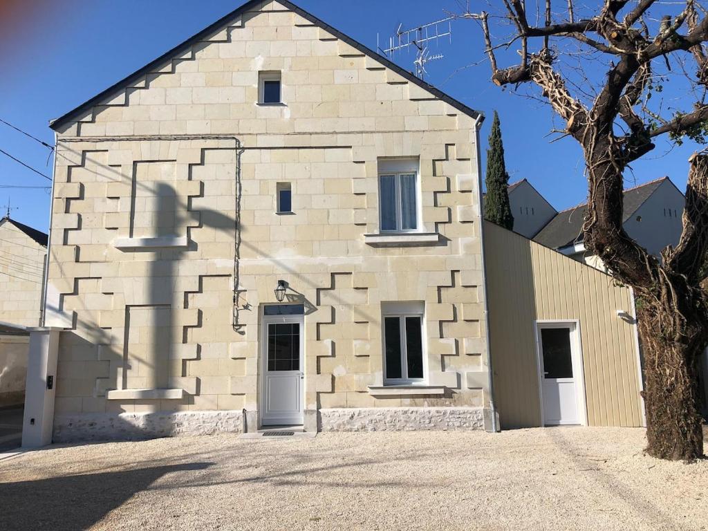 un grand bâtiment en pierre avec un arbre au premier plan dans l'établissement Maison Saumur, à Saumur