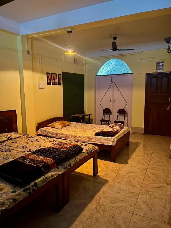 una stanza con due letti e una finestra di Heritage Inn Homestay Sivsagar a Sibsāgar