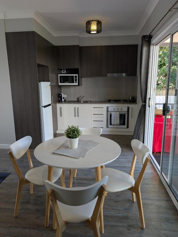 a kitchen with a white table and chairs and a table and a kitchen at Southern Comfortable in Goolwa North