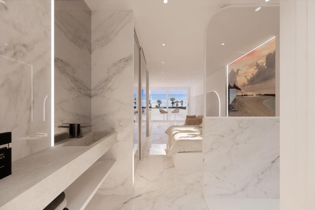 une chambre blanche avec un lit et une vue sur l'océan dans l'établissement Naturiste Cap d'Agde Héliopolis AB 30, au Cap d'Agde