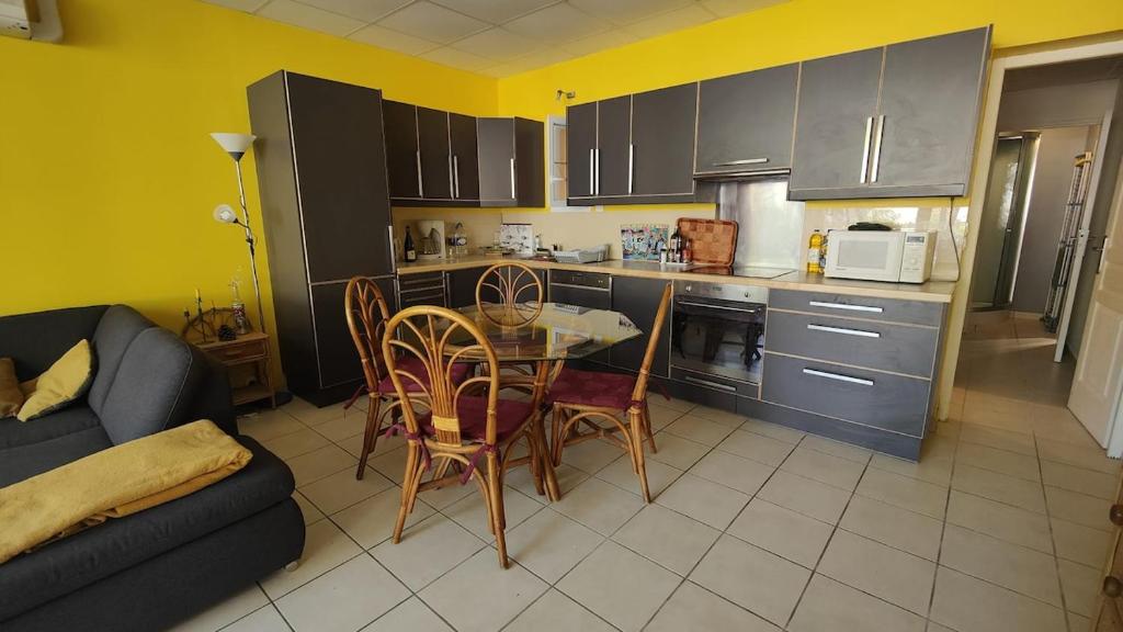 une cuisine avec une table, des chaises et un canapé dans l'établissement Appartement au calme en rdc, à Banyuls-sur-Mer