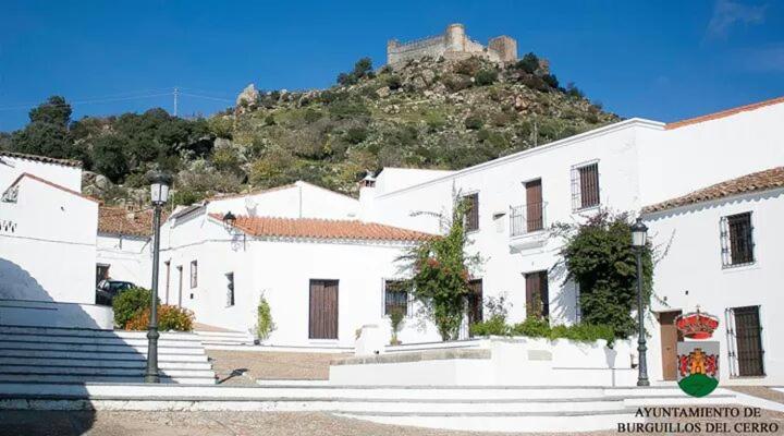 a white building with a mountain in the background at Hostal El Camionero in Burguillos del Cerro