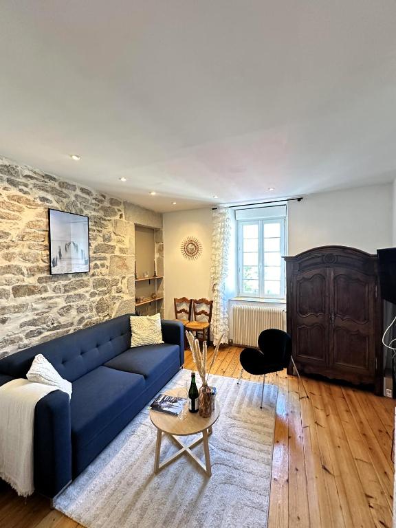 - un salon avec un canapé bleu et un mur en pierre dans l'établissement Maison de charme Locmaria, à Quimper
