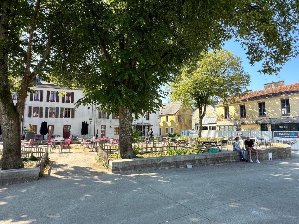 a group of people sitting in a park with trees at Maison de charme Locmaria in Quimper
