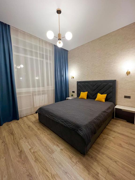 a bedroom with a bed with blue curtains and yellow pillows at 2х комнатная квартира ЖК Арман in Kokshetau