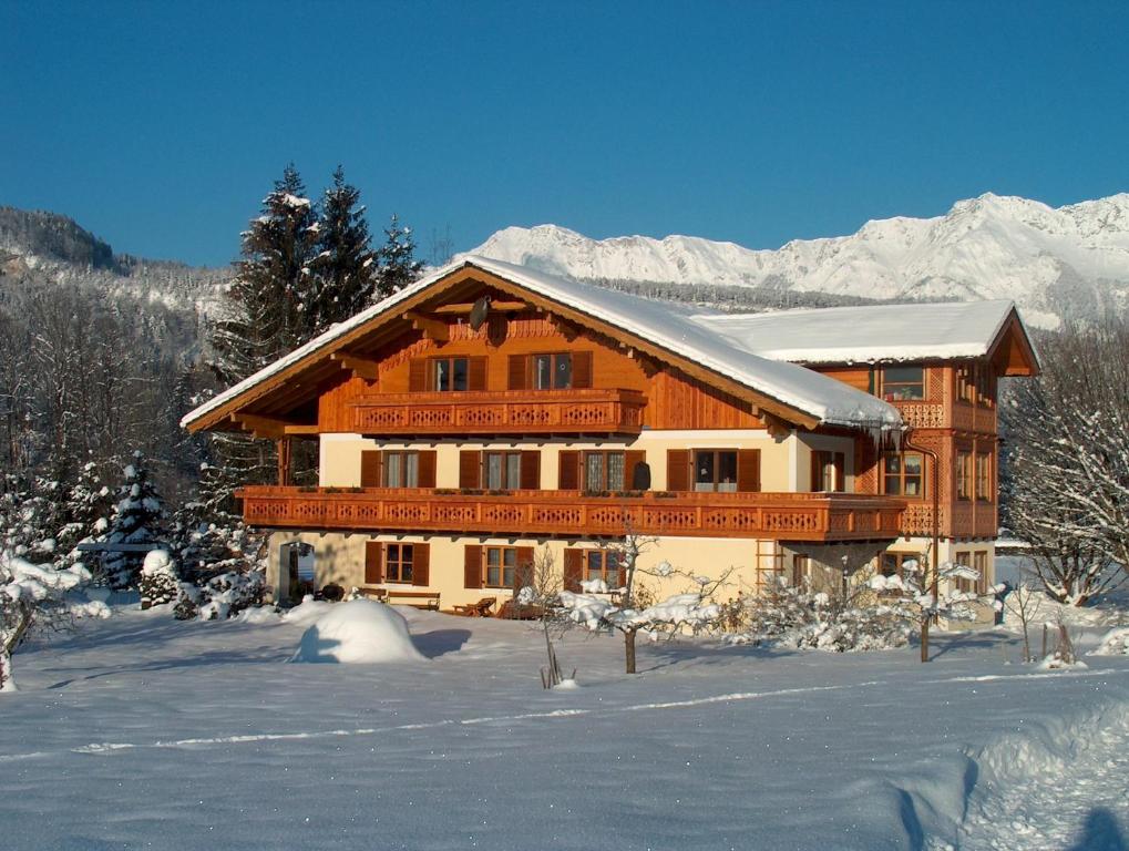 a large wooden house in the snow with mountains at Haus Puntigam in Bad Goisern