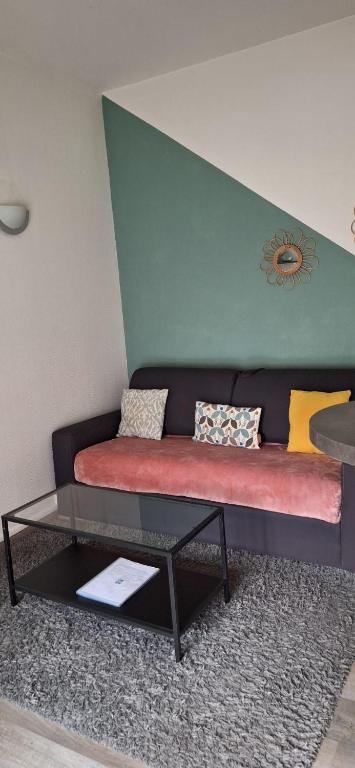 un canapé avec des oreillers et une table dans une pièce dans l'établissement Appart'Jardin, à Saint-Pierre-des-Corps