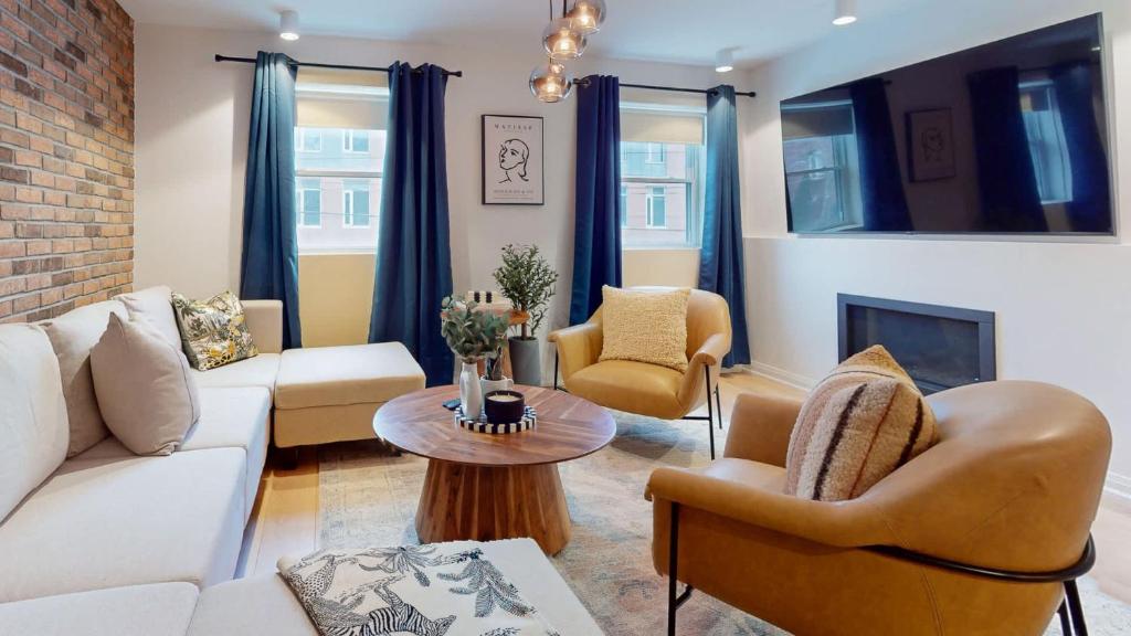 a living room with a couch and chairs and a fireplace at Casa East Side Hotel Queen East Leslieville Suite in Toronto
