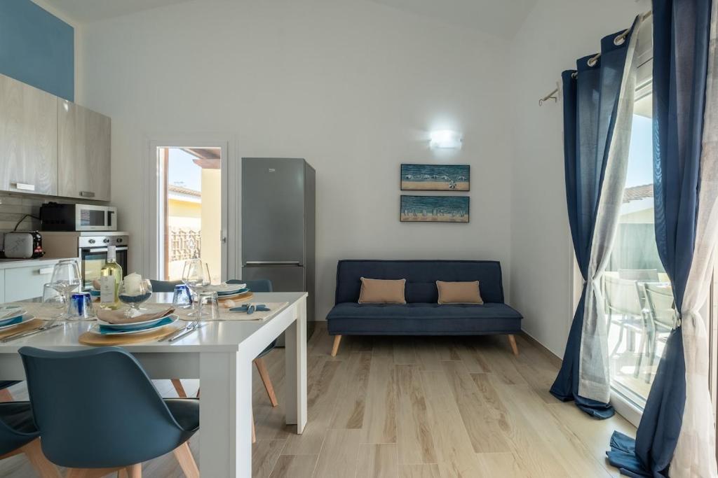 uma sala de estar com uma mesa branca e um sofá azul em Villa Daniela- Costa Rei a 5 minuti a piedi dalla spiaggia con AC, WiFi e Parcheggi Privati em Costa Rei