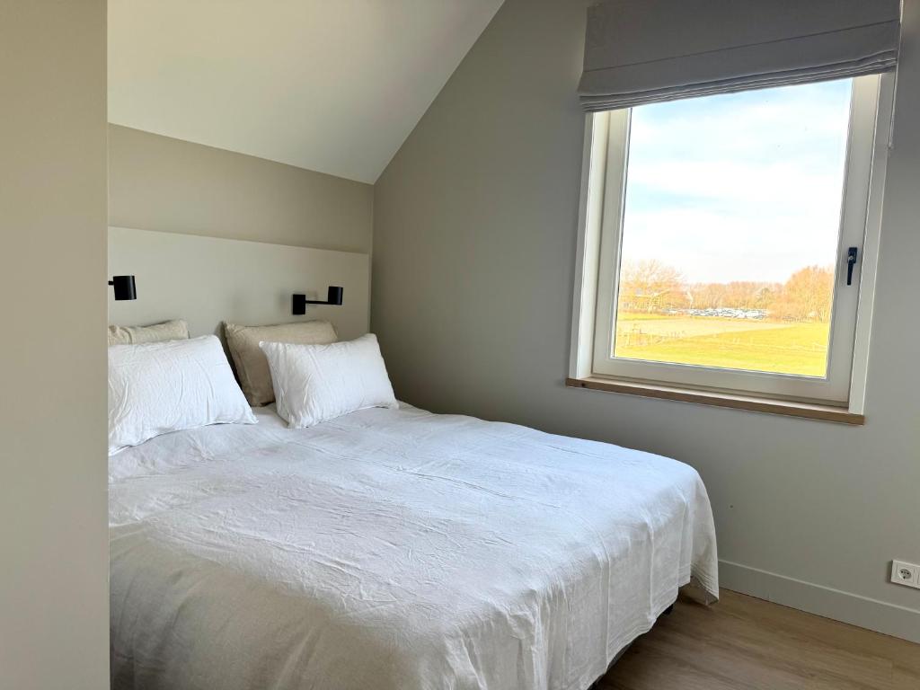 ドンブルグにあるVrijvakantiehuis Brouwerijweg 45aの白いベッドと窓のある寝室