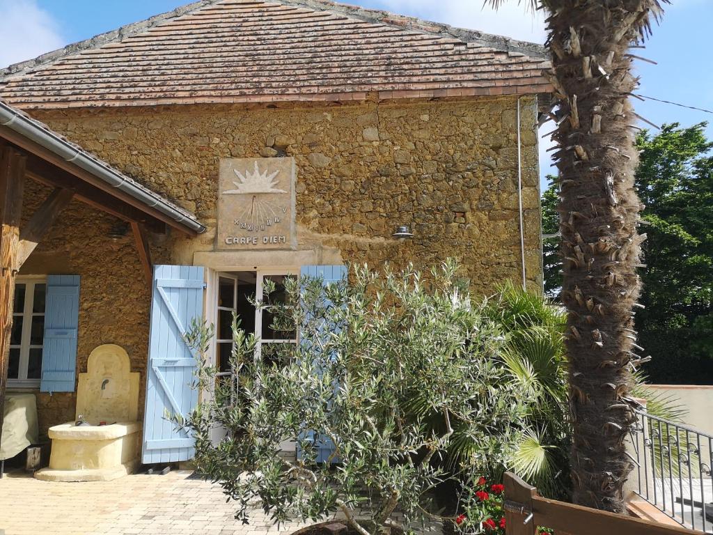 a brick building with a blue door and a palm tree at Chez Jay à Bassoues in Bassoues