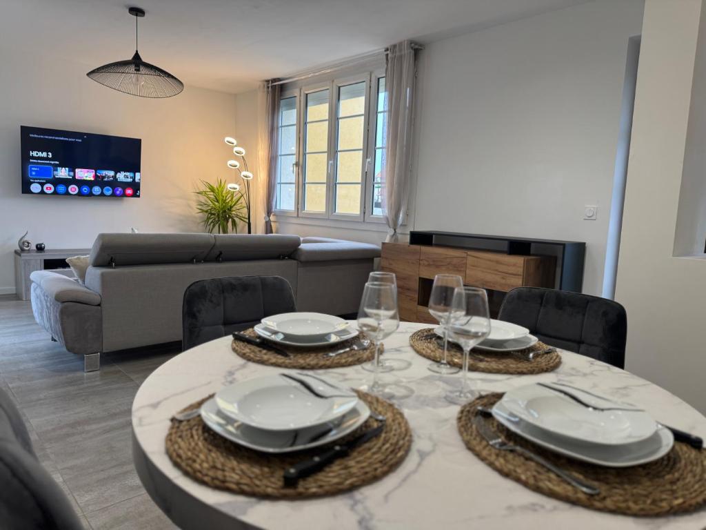 - un salon doté d'une table avec des assiettes et des verres à vin dans l'établissement Mancelle proche du circuit 24h, au Mans