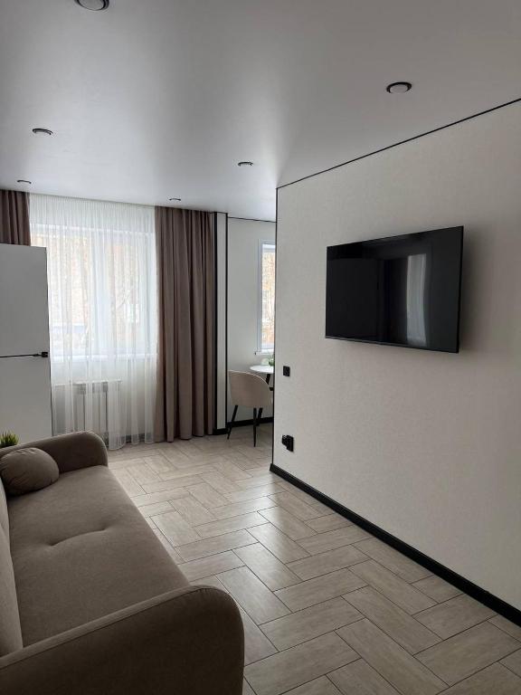a living room with a couch and a television on a wall at Торайгырова 89 in Pavlodar