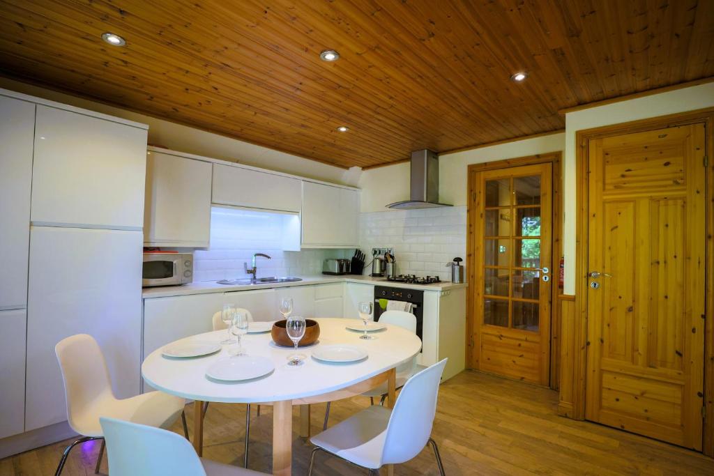 a kitchen with a white table and white chairs at Fern Gully Lodge with Hot Tub - Spa Resort - Devon in Chudleigh