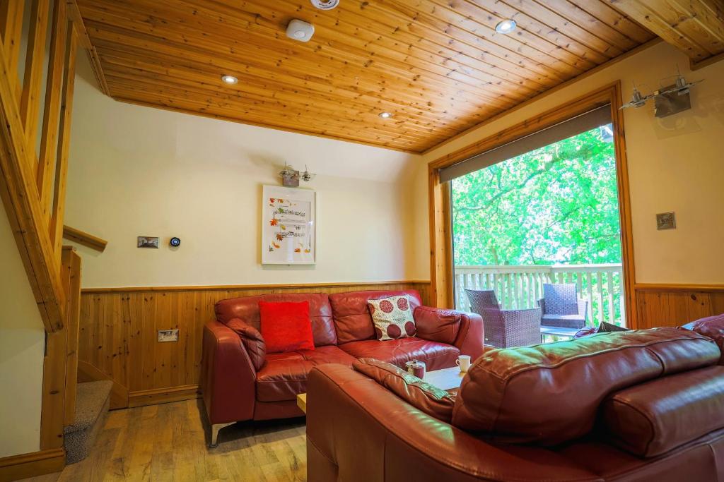 a living room with a couch and a large window at Fern Gully Lodge with Hot Tub - Spa Resort - Devon in Chudleigh
