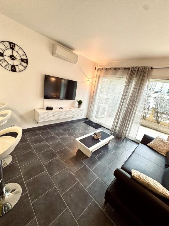 un salon avec un canapé et une télévision dans l'établissement Appartement terrasse - 50m plage, à Canet