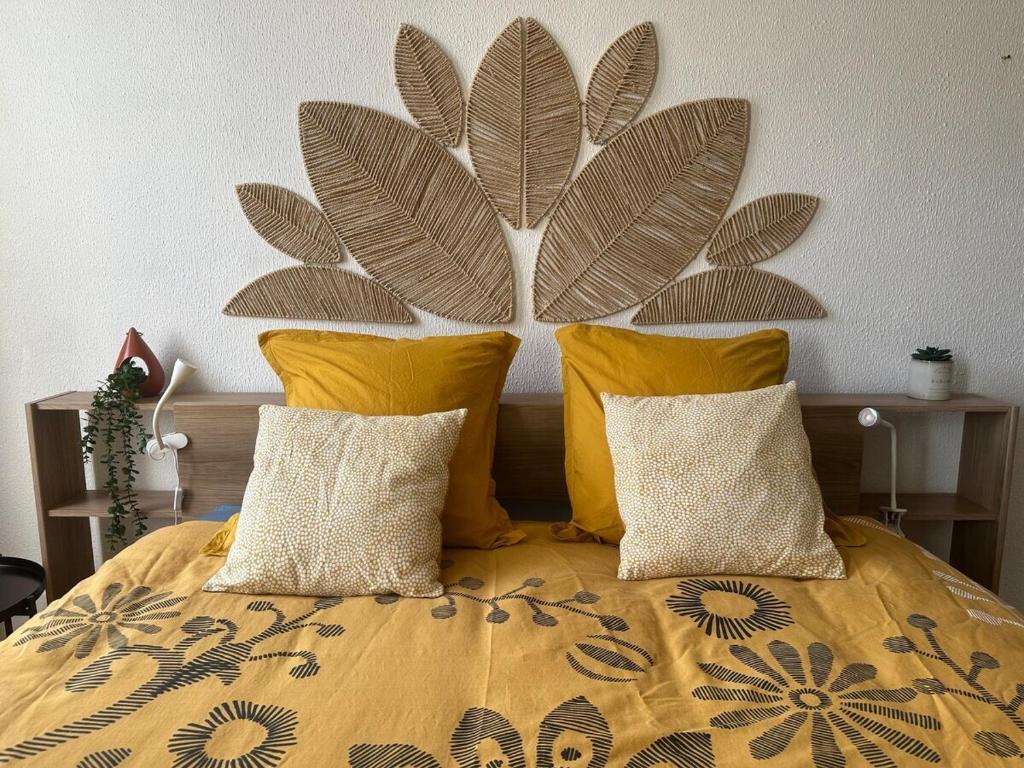 a bed with yellow pillows and a large painting on the wall at Appartement cosy au coeur de la ville d'Auch in Auch