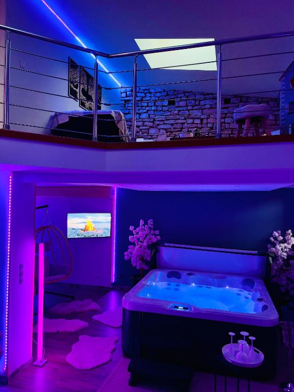 Cette chambre violette dispose d'une baignoire et d'une télévision. dans l'établissement LOFT Aux Retrouvailles -Gîte avec Spa De 2 à 6 personnes, à Moriviller