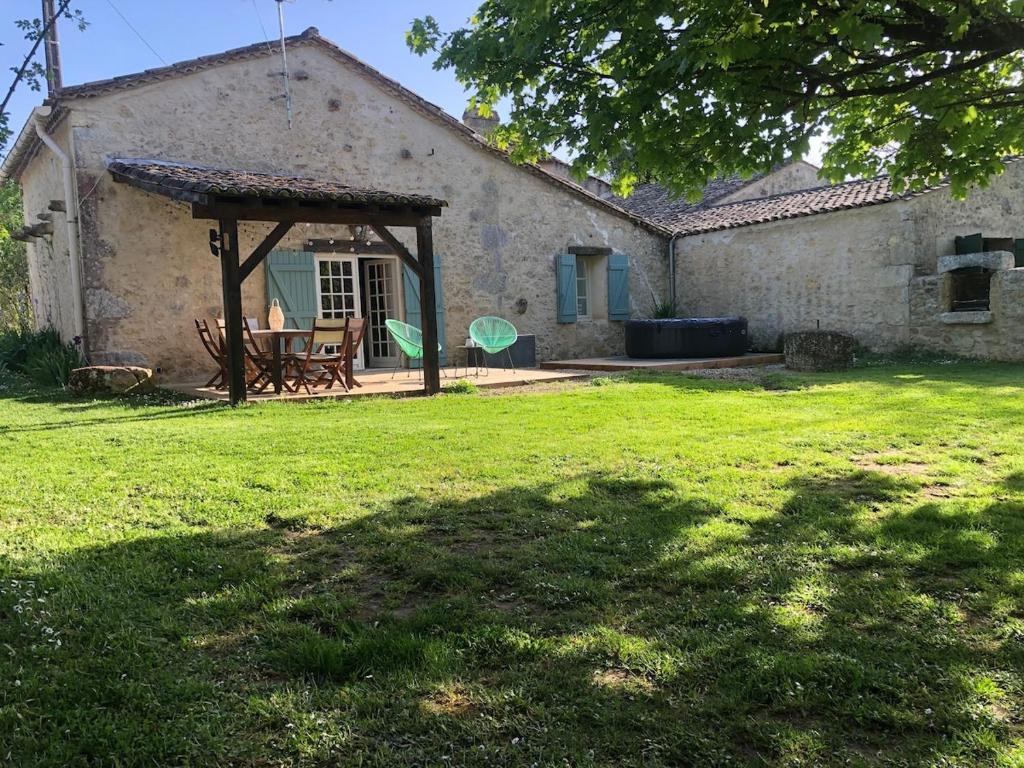 une vieille maison en pierre avec une table de pique-nique dans la cour dans l'établissement L'Orée des Vignes, à Montcaret
