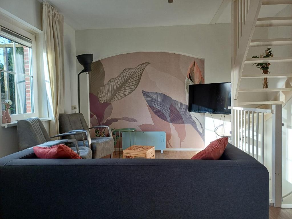 a living room with a blue couch and a tv at Natuur Appartement Dinxperlo in Dinxperlo