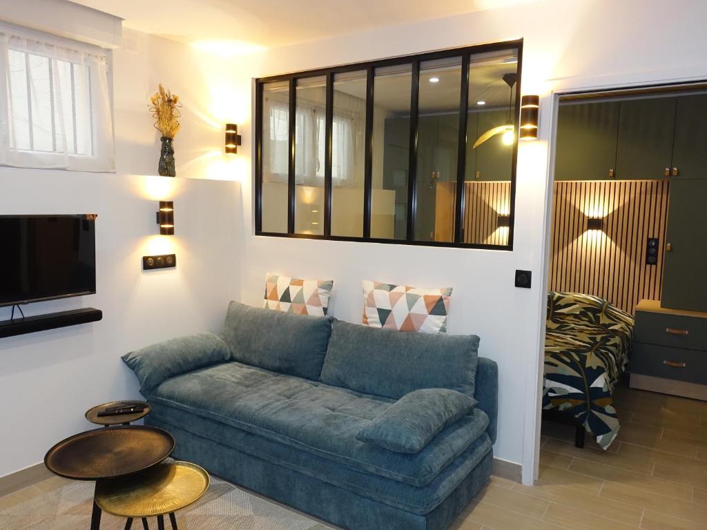un salon avec un canapé bleu et une télévision dans l'établissement Appartement cosy - proximité rue du Commerce, à Paris