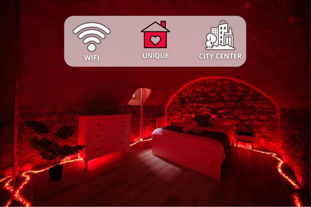 - une chambre dotée d'un lit avec des lumières rouges et un panneau dans l'établissement The secret cave, à Reims