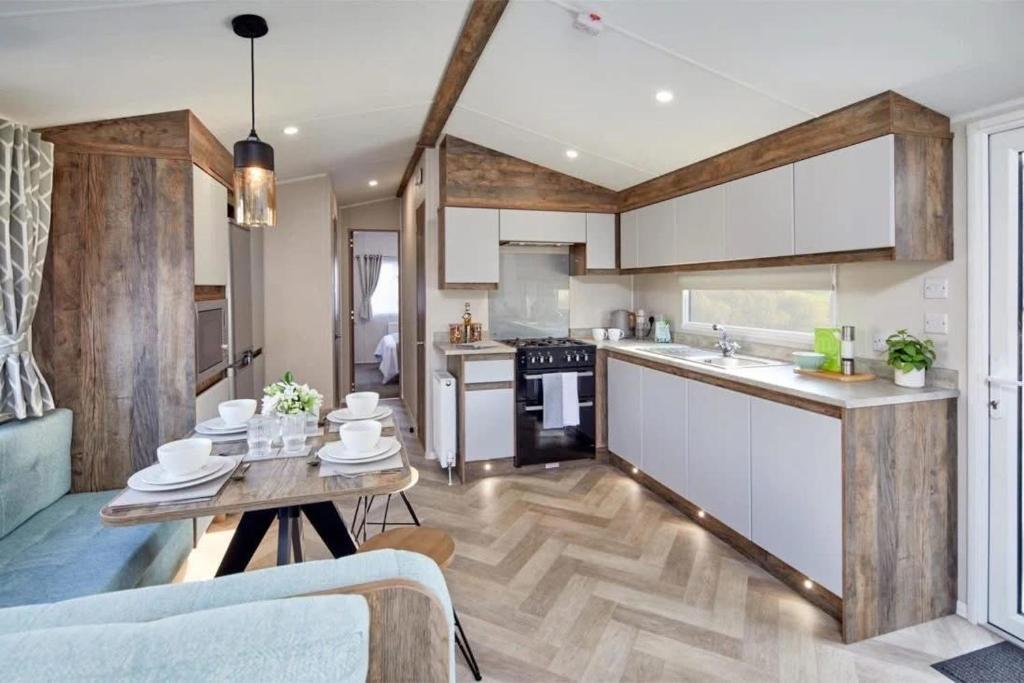 a kitchen with white cabinets and a wooden floor at Lakeside Retreat - AGH Hot Tub Breaks - Tattershall Lakes in Tattershall