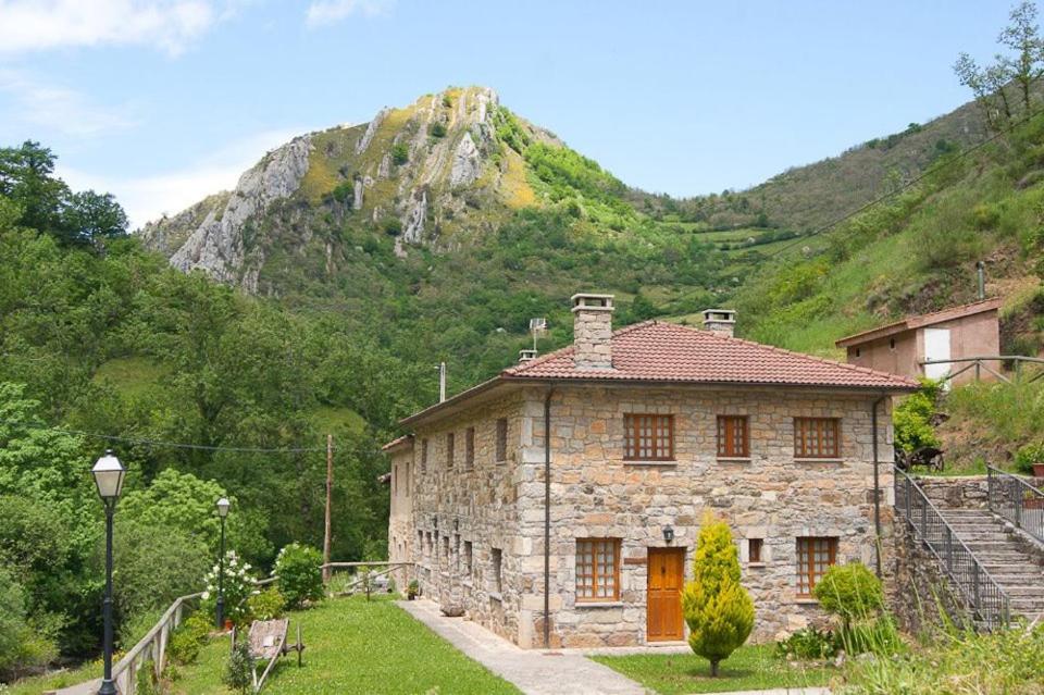 uma antiga casa de pedra em frente a uma montanha em Apartamentos Rurales Casa Marcelo em Veigas