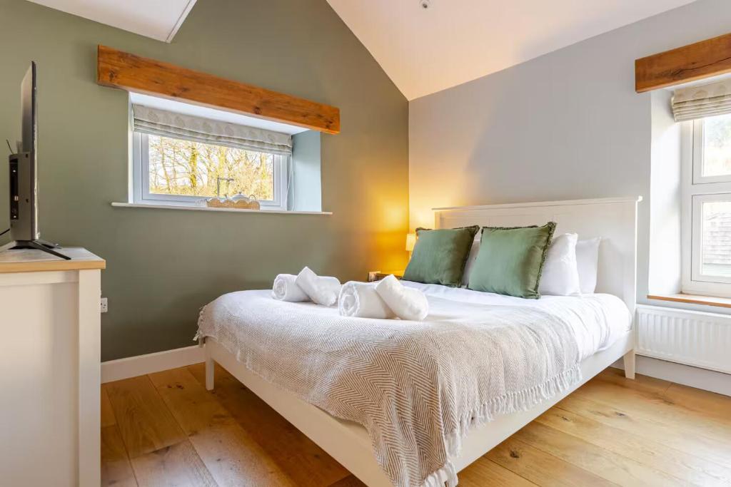 a bedroom with a bed with green and white pillows at Luxurious Cosy Cottage in Buxton