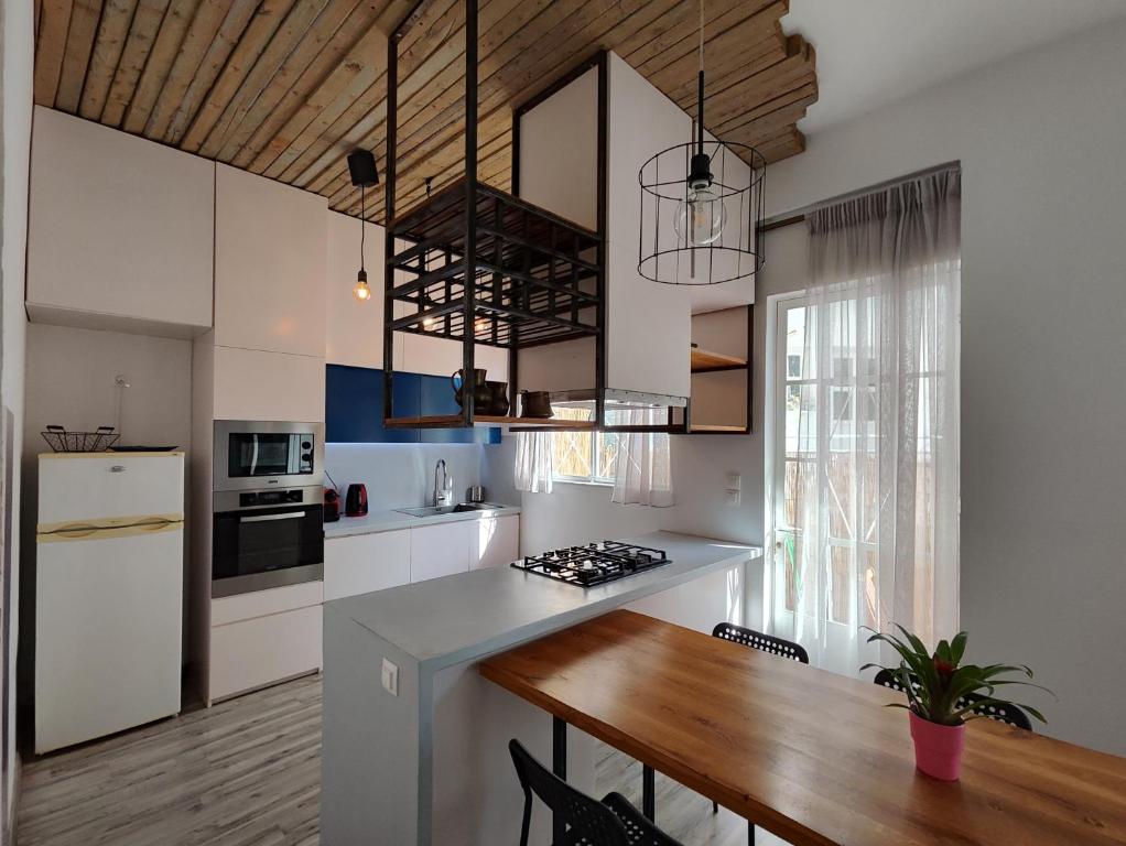 a kitchen with white cabinets and a wooden table at Superior Apartment Near Beach in Chania