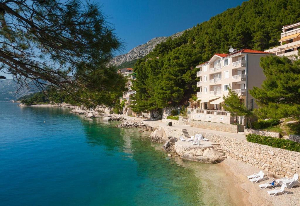 a beach with chairs and buildings next to the water at Apartments and Room Luxury dream in Brela